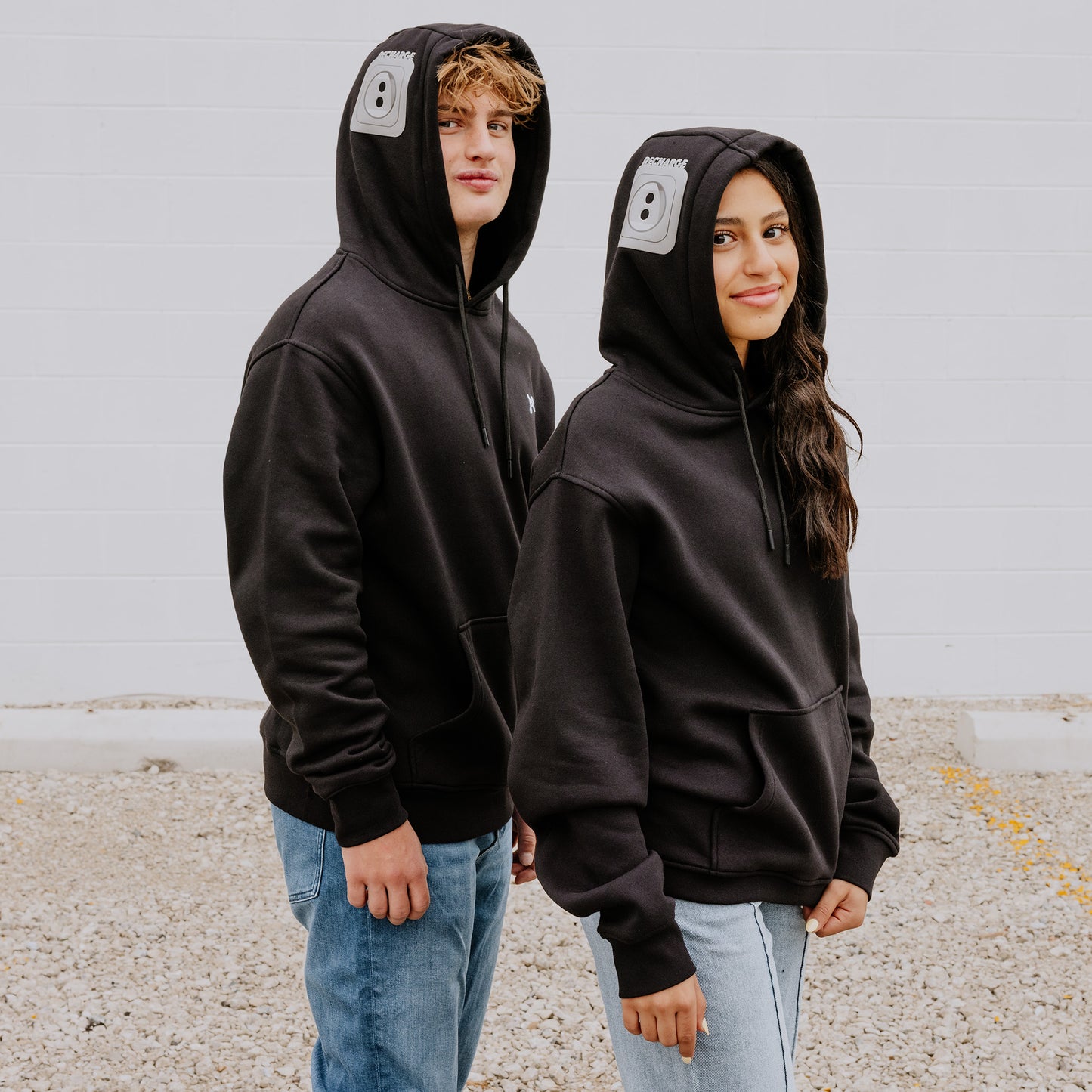 Two teens rocking black OOsmash Plug Hoodies with gray outlet design—recharge your energy, own your vibe