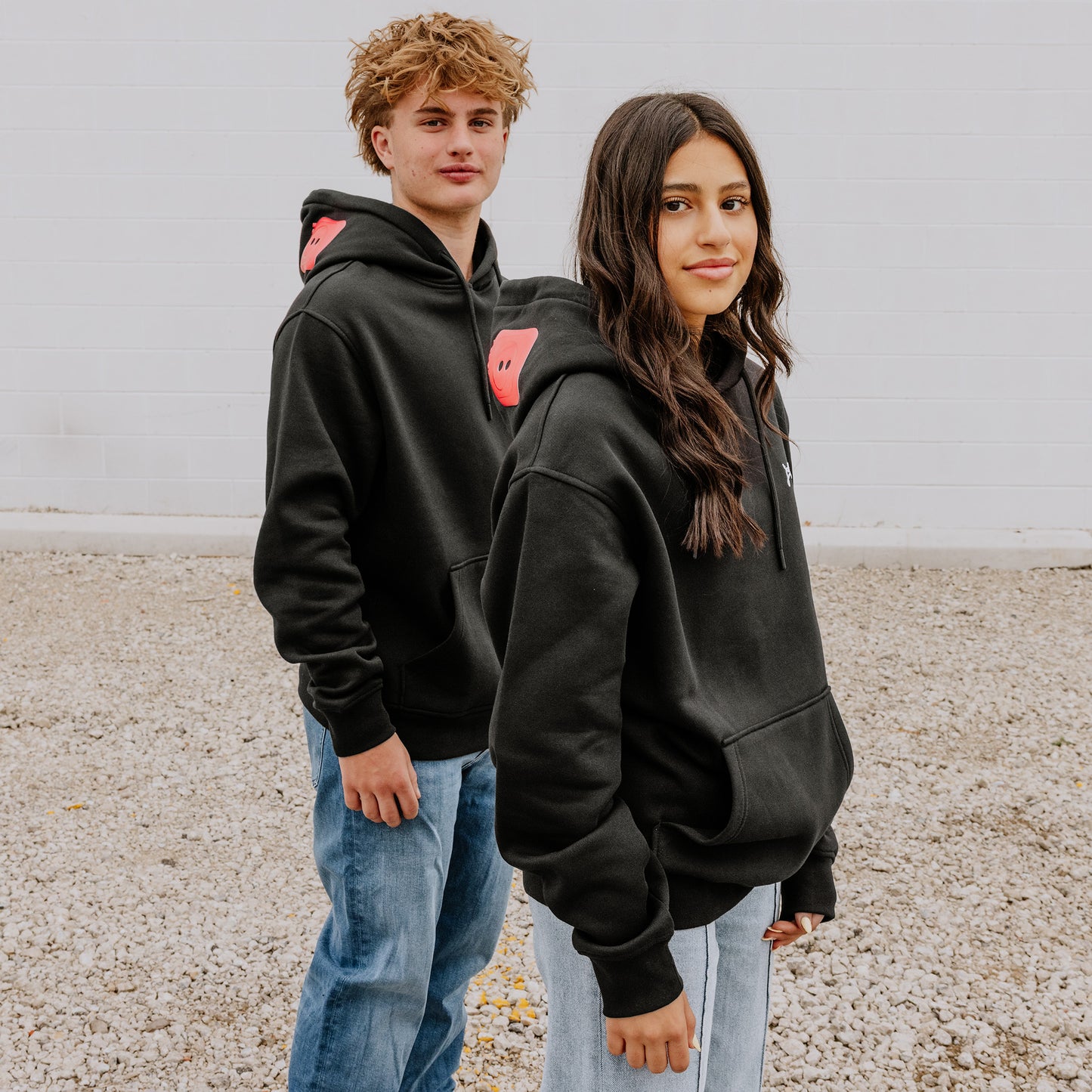Two Models wearing OOsmash black hoodie featuring bold red plug - unstoppable crew graphic.