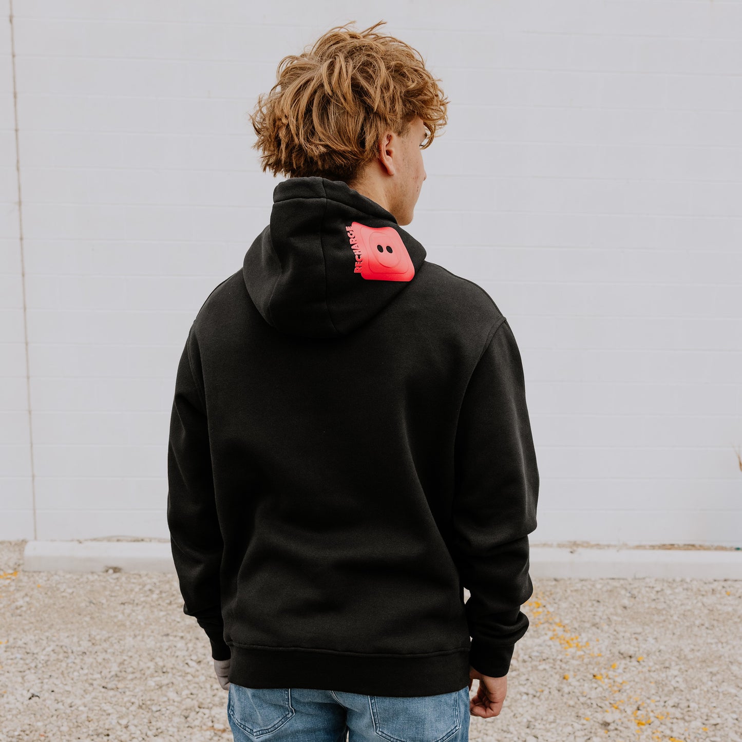 Model wearing OOsmash men’s black hoodie featuring bold red plug accent and relaxed fit.