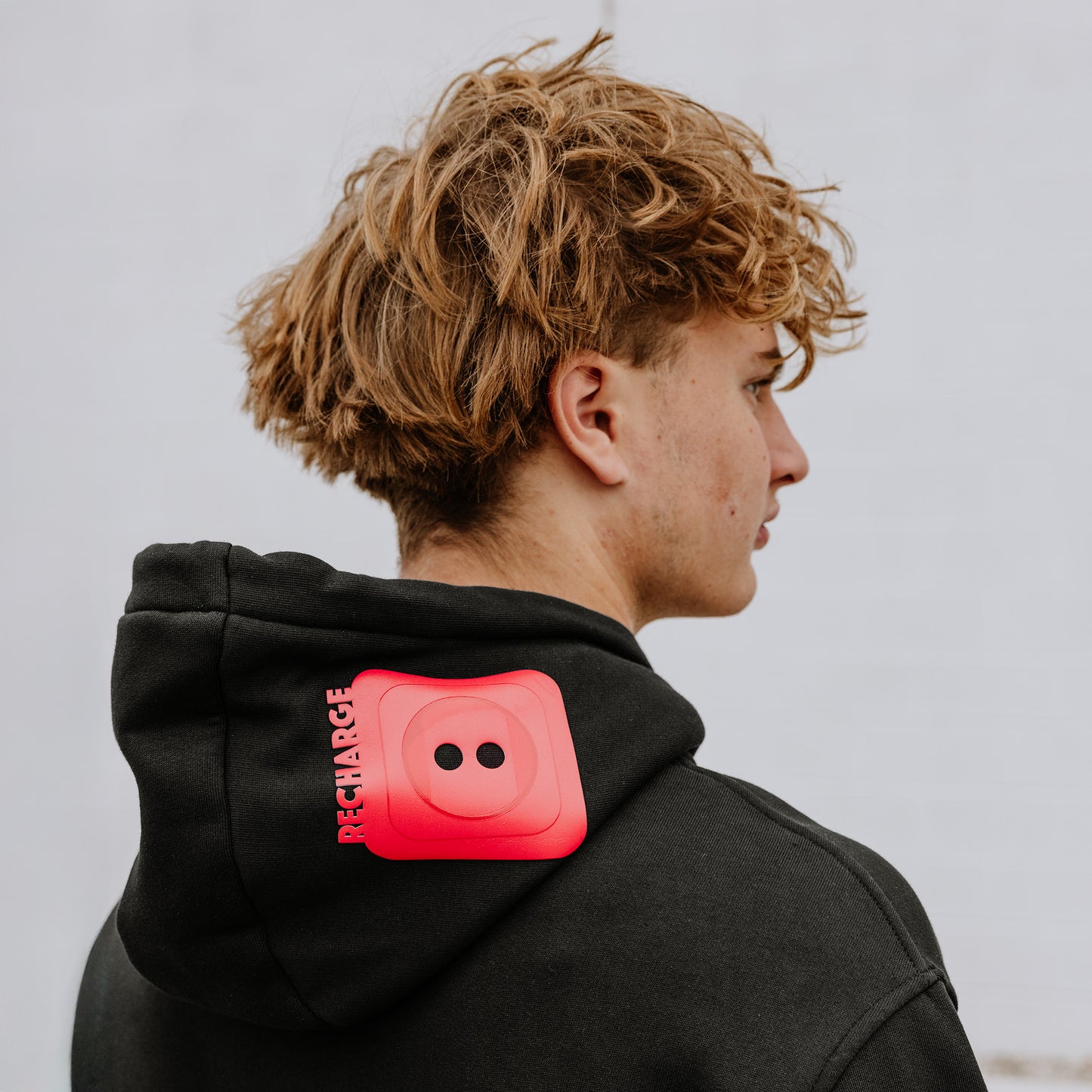 Model wearing OOsmash men’s black hoodie featuring bold red plug accent and relaxed fit.