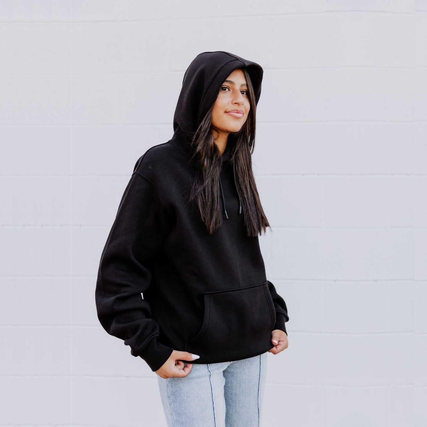 Model wearing OOsmash women’s black Connected hoodie featuring relaxed fit and adjustable hood.