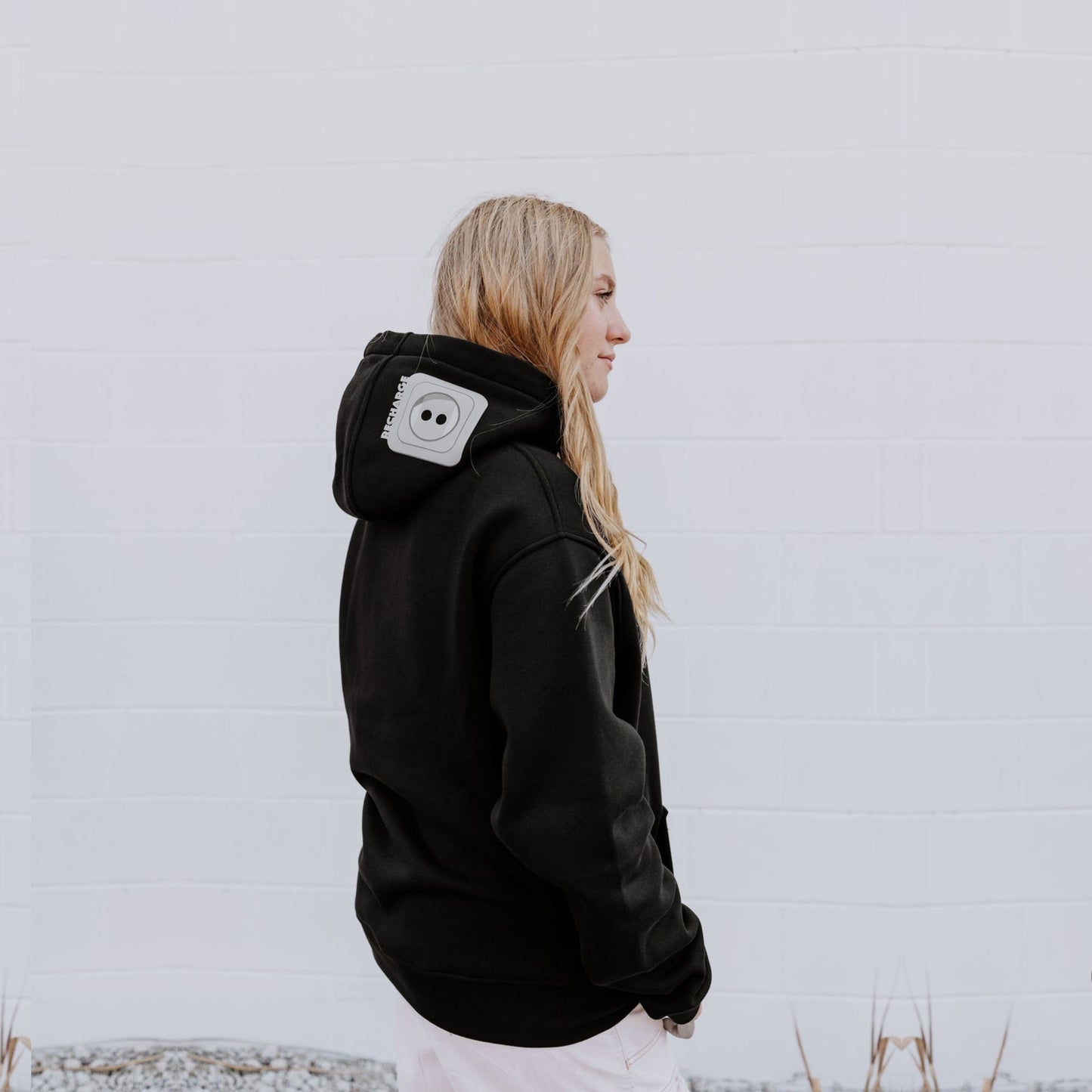 Model wearing OOsmash women’s black hoodie featuring gray plug accent and relaxed fit.