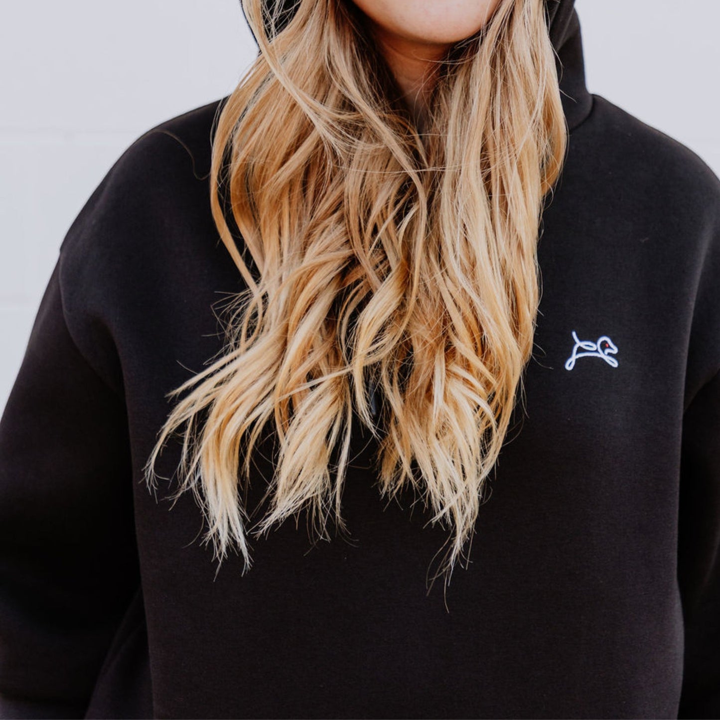 Model wearing OOsmash women’s black hoodie featuring bold red plug graphic.