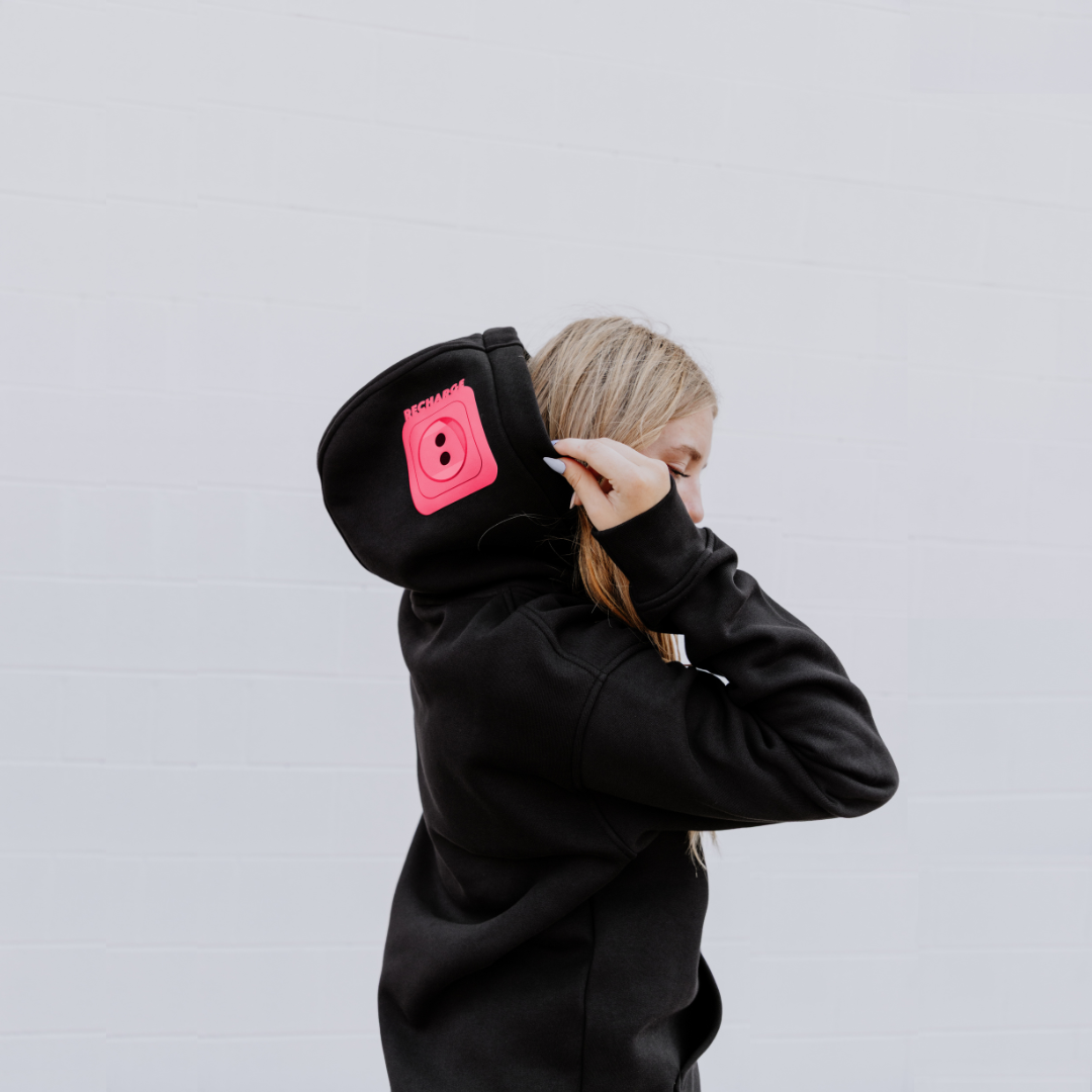 Model wearing OOsmash women’s black hoodie featuring bold red plug graphic.