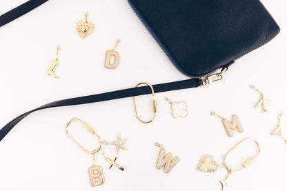 OOsmash 18K Gold Plated Charm Carabiner — gold plated carabiner and letter charms flat lay next to handbag, personalized luxury bag accessory gift
