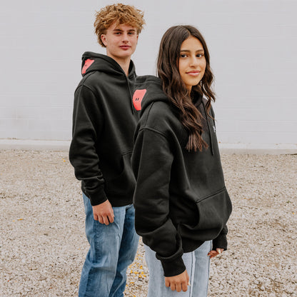 Two Models wearing OOsmash black hoodie featuring bold red plug - unstoppable crew graphic.