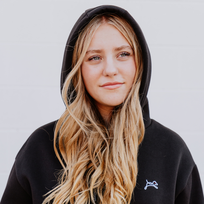 Model wearing OOsmash women’s On/Off Line hoodie in black featuring relaxed fit and adjustable hood.