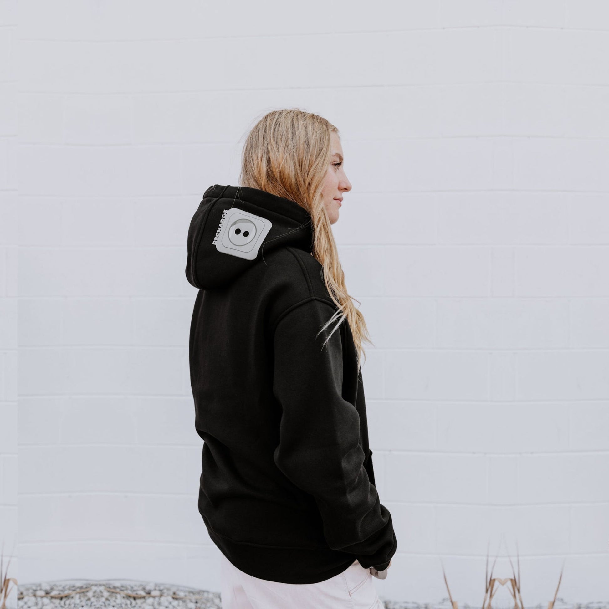 Model wearing OOsmash women’s black hoodie featuring gray plug accent and relaxed fit.