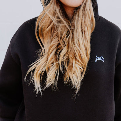 Model wearing OOsmash women’s black hoodie featuring bold red plug graphic.